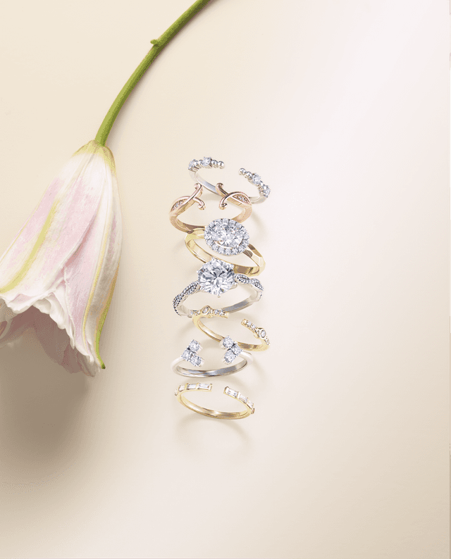 Stack of Motek Jewelry white, yellow, and rose gold diamond engagement rings with lily flower.