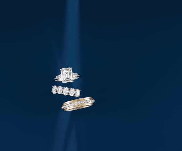 Motek Jewelry emerald-cut diamond three-stone engagement ring paired with platinum and gold eternity bands.