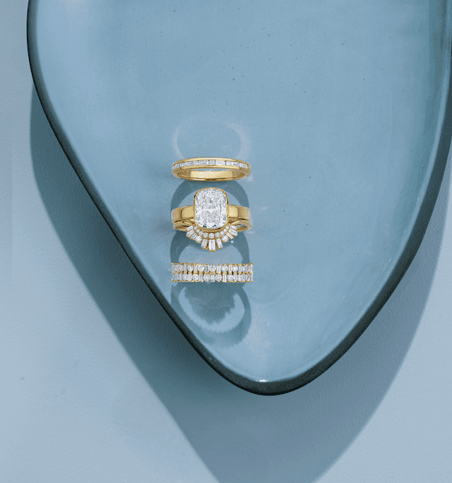 Motek Jewelry emerald-cut diamond bridal ring set and curved wedding bands in yellow gold.