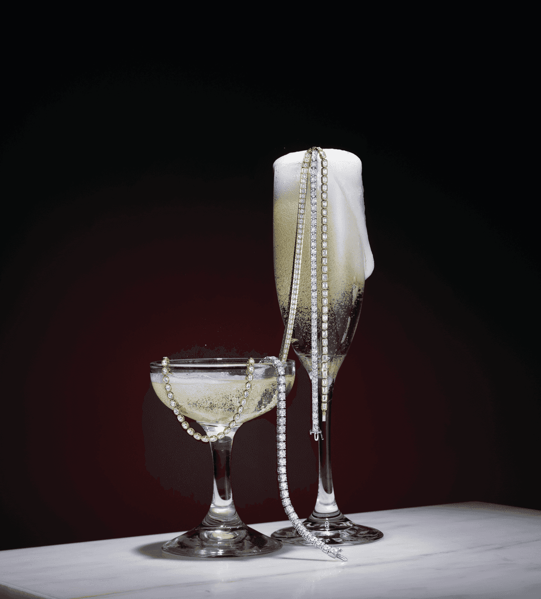 Motek Jewelry sparkling diamond tennis bracelets and necklaces draped over champagne flutes.