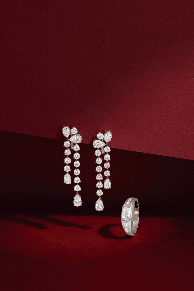 Elegant Motek Jewelry multi-tier pear-cut diamond chandelier earrings displayed on a dramatic crimson red backdrop.