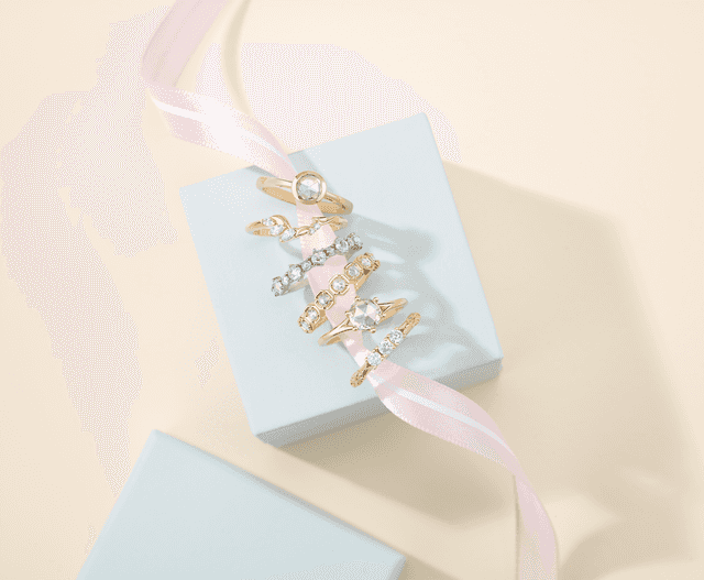 Motek Jewelry collection of yellow and white gold diamond eternity bands styled on a pastel gift box.